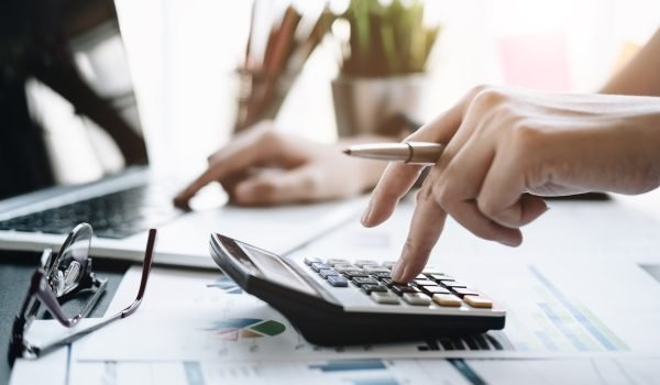 Close up Business woman using calculator and laptop for do math finance on wooden desk in office and business working background, tax, accounting, statistics and analytic research concept